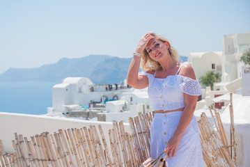 Fototapeta na wymiar Woman in trip, Picturesque view of traditional Santorini streets, Location: Oia village, Santorini, Greece. Vacations and adventure concept