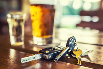 Car keys and glass of beer or distillate alcohol on table in pub or restaurant