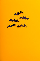 Crafts for the concept celebration of Halloween. Figures of a black bat, cut from black paper on yellow background. Place for text Mock up Top view