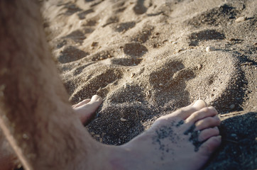 Guy's feet in the sand on the beach