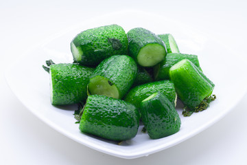 Canned cucumbers on a white plate with leaves and water droplets