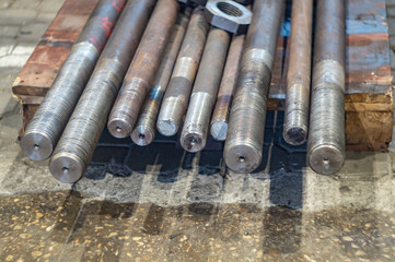 Nuts and studs after turning the threading on the rack in the workshop.