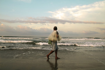 Pescador caminando a la orilla del mar mirando el horizonte.