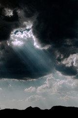Obraz na płótnie Canvas Rayos de luz atravesando el cielo negro, con montañas en el fondo