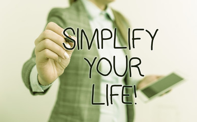 Text sign showing Simplify Your Life. Business photo text focused on important and let someone else worry about less ones Business woman pointing in empty space with pen and mobile phone