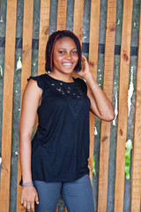 Young african american woman posed against wooden wall.