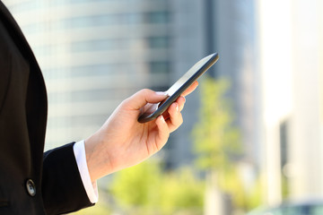 Businesswoman hand using a smart phone in the street