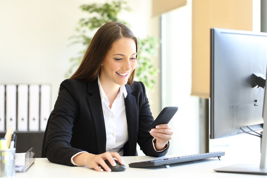 Happy businesswoman checking phone text at office