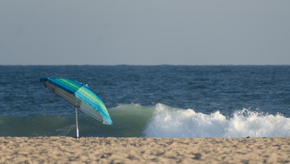 Alone umbreall between sand line and strong surf