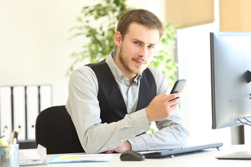 Naklejka premium Serious executive holding phone looking at camera