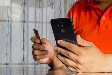 Compra en línea con tarjeta de crédito. Closeup de manos de joven hombre con teléfono inteligente para ir de compras en línea y pagar con tarjeta de crédito. Concepto en línea de compras