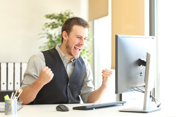 Excited businessman checking good news on computer