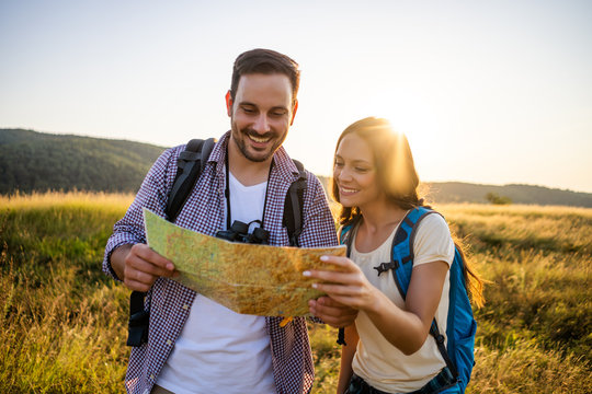 Happy Couple Is Hiking In Mountain. They Are Looking At Map.