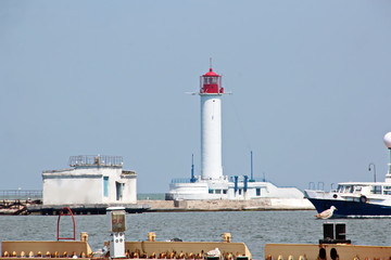 View of the lighthouse of the port of Odessa against the background of piers and blue sky. Summer 2019.