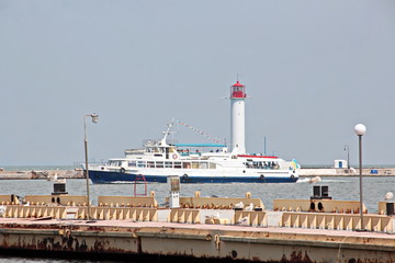 View of the lighthouse of the port of Odessa against the background of piers and blue sky. Summer 2019.