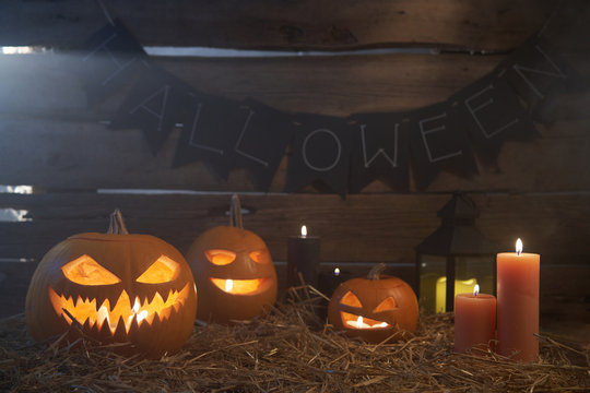 Jack-O-Lantern Halloween pumpkins on rough wooden planks with candles