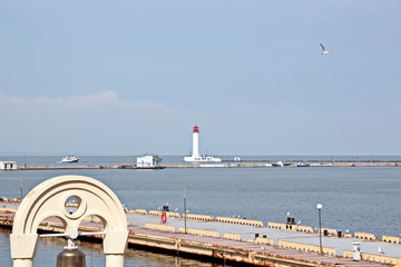 View of the lighthouse of the port of Odessa against the background of piers and blue sky. Summer 2019.