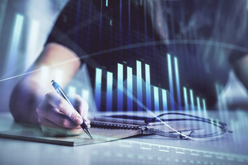 Multi exposure of woman's hands making notes with forex graph hologram. Concept of technical...