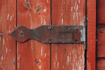 Vintage door hinge. Rusty metal hinge on red wood close up detail view