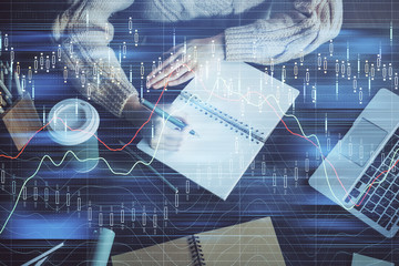 Forex graph on hand taking notes background. Concept of research. Double exposure