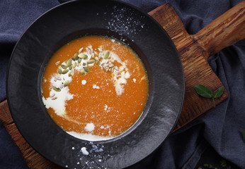 Pumpkin soup in a black plate on a dark background