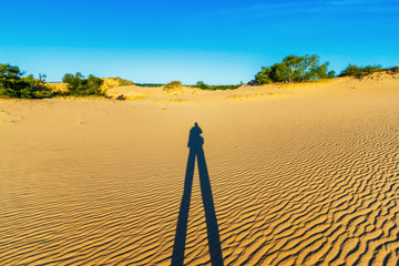 The sandy desert landscape with the long shadow of a man - Powered by Adobe