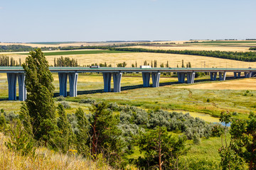 The summer sunny landscape with a car bridge among farmland fields. Highway M4 