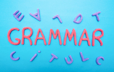 The word grammar on a blue background and letters scattered in a chaotic manner, the concept of literacy at school, inscription