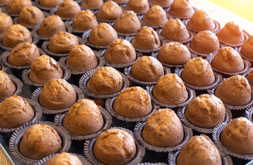Lots of delicious fresh chocolate muffins muffins on a tray, background, copy space, dessert, manufacturing