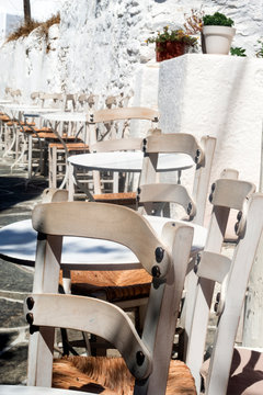 Greece, the island of Sikinos. A narrow alleyway in the heart of the Kastro, the islands capitol.  Taverna tables and chairs lined up for the evening’s diners. A summers day in this peaceful village.