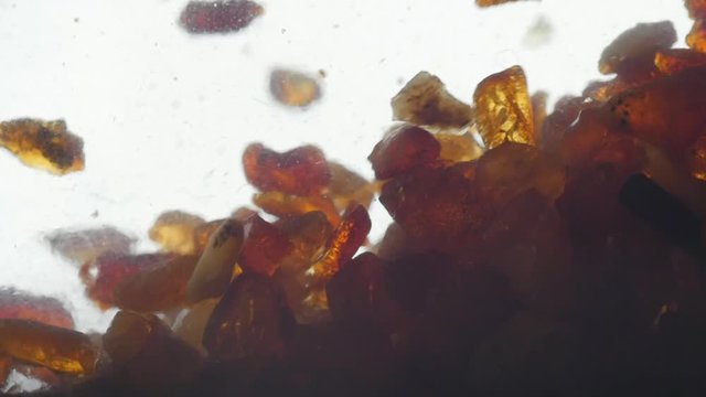pieces of amber in water falling to the bottom slow motion