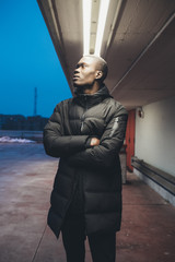 portrait of young african man standing in the street and looking away