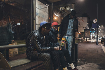 three young african men waiting on the bus stop