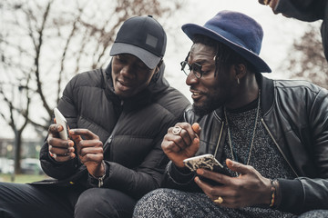 two african friends sitting outdoor and looking the smartphone