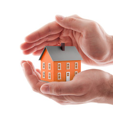 Small orange toy house protected by hands isolated on white