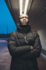 portrait of young african man standing in the street and looking away