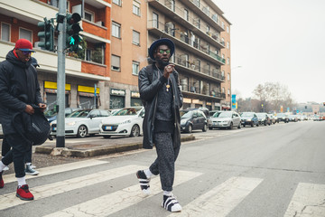 Fototapeta premium young african man standing in the street and smoking cigar