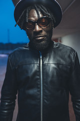 portrait young black man standing in the street and looking camera
