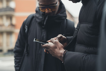 close up young african man hands outdoor using smartphone