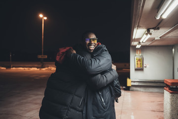 two young african men outdoor together hugging having fun