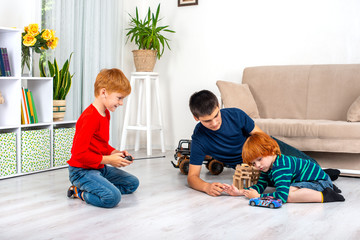 Two little boys with older brather  sit on the floor in the room and play with the machine