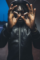 portrait of young black man standing outdoor with open hands looking the camera
