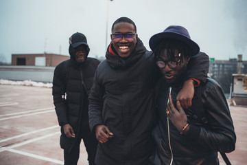 three young african men outdoor together hugging having fun