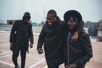 three young african men outdoor together hugging having fun