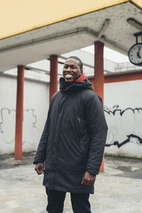 young man african posing outdoors looking camera smiling