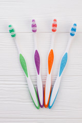 Set of colorful tooth brushes on white wooden background. Four different tooth brushes on wooden table.
