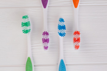 Four colored tooth brushes on white wooden table. Set of multicolored toothbrushes on wooden background. Equipment for teeth cleaning.