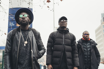 three young black men walking in the street and looking further