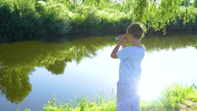 Cute white kid watching through old telescope at something intersting far away in distance. Real time 4k video footage.