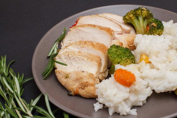 Baked chicken breasts or fillet on plate with rice and vegetables on plate.